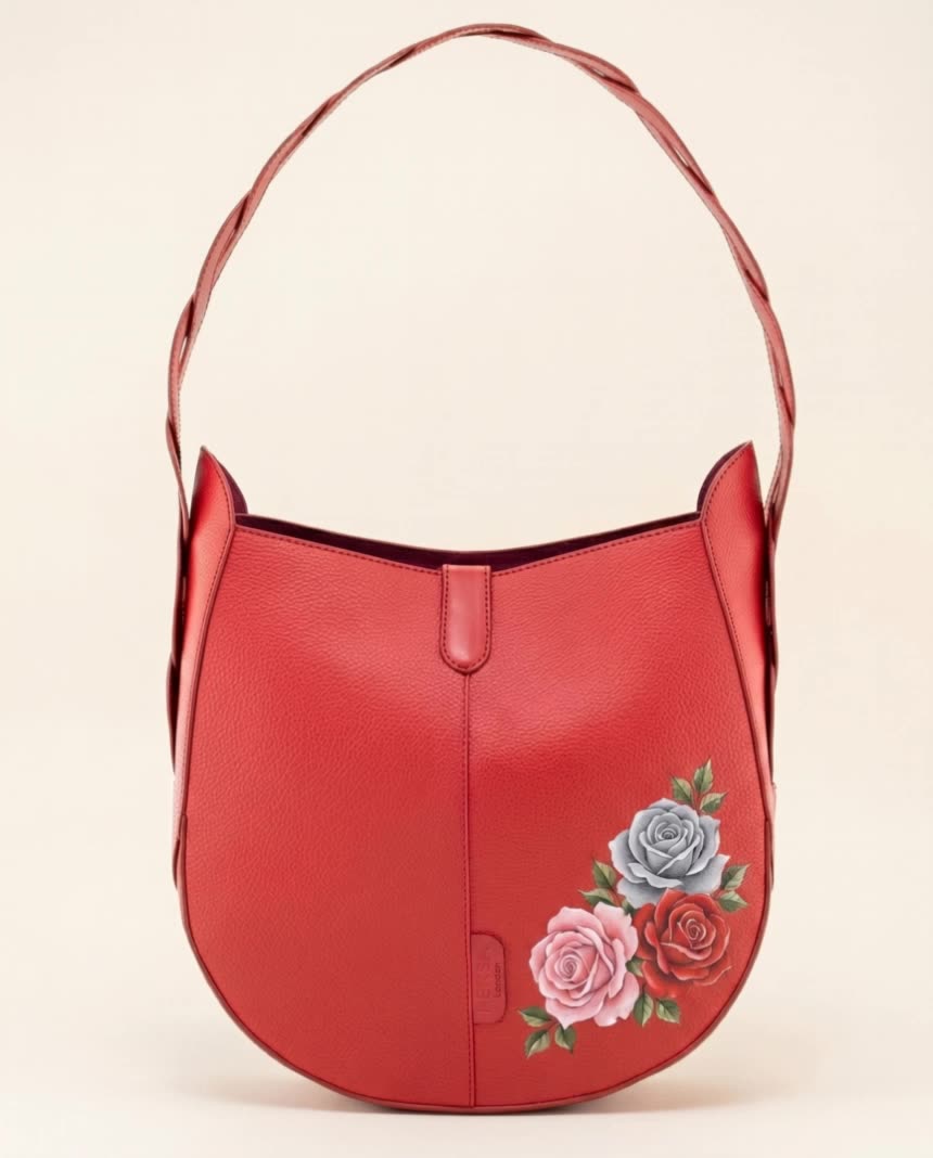 Hand-painted rose-motif leather shoulder bag resting on cream